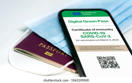 The digital green pass of the european union with the QR code on the screen of a mobile phone over a surgical mask and a passport. Immunity from Covid-19. Travel without restrictions. - Shutterstock ID 1963190500
