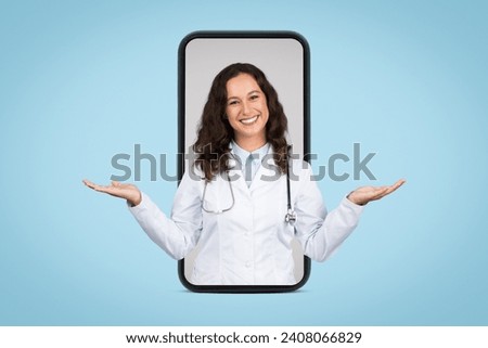 Digital healthcare concept with smiling female doctor displayed inside smartphone frame, hands raised in balancing gesture on blue background