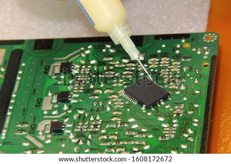 Digital home electronics maintenance, applying flux solder from a syringe to the processor pins on PCB for solding close up