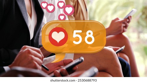 Digital image of a heart icon and increasing numbers inside a yellow chat box. There are people in corporate attires seated in a row while checking their phones 4k - Powered by Shutterstock - Get 15% off with code: PIKWIZARD15