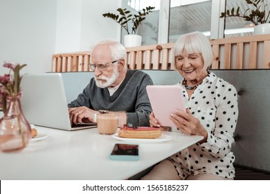 Digital Immigrants. Pleasant Elderly People Using Digital Devices While Sitting In The Cafe