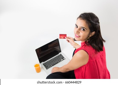 Digital India Concept - Beautiful Looking Indian Young Girl Working On Laptop And Using Debit/credit/ATM Card For Making Payment Online, Sitting Over White Background