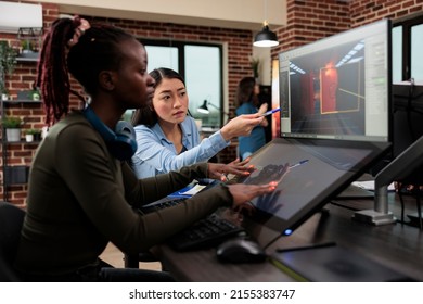 Digital interactive entertainment industry workers working with CGI. Game development creative agency artists conversating about level design and 3D assets while sitting in office workspace. - Shutterstock ID 2155383747
