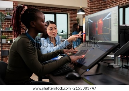 Digital interactive entertainment industry workers working with CGI. Game development creative agency artists conversating about level design and 3D assets while sitting in office workspace.
