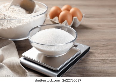 Цифровая кухонная весы с чашей сахара и других продуктов на деревянном столе, закрытие