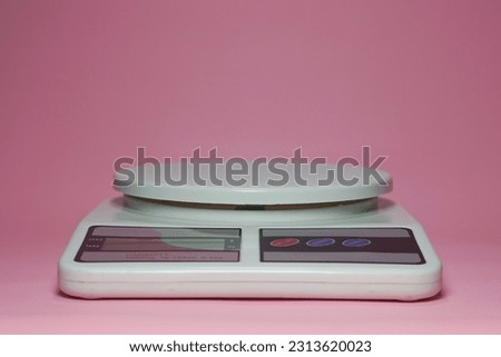 Digital kitchen scale with a capacity of 10 kilograms, LED display and three keypad buttons. Portable digital scales with a white plastic case on pink background isolated.