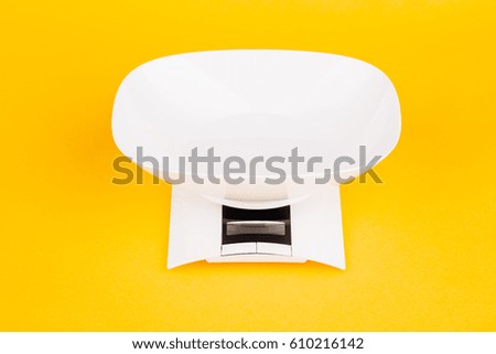 Digital kitchen weight scale on yellow background