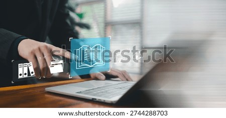 Digital knowledge management and online documentation concept with virtual book icon over laptop. E learning, cloud storage, data archive, information access and business training technology.