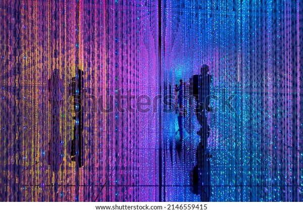 Digital Life concept. Abstract of shadow of\
person standing in middle of a room full of infinite colorful LED\
light illumination.