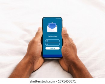 Digital Marketing. Black Man Holding Smartphone With Newsletter Subscription Form And Opened Envelope Icon On Screen While Relaxing In Bed, Creative Collage For Email Communication, Copy Space