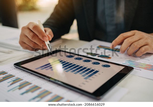 Digital marketing, businessman using smart tablet\
and documents on office desk background. Concept for business\
strategy, economy and\
tax.