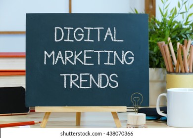 Digital Marketing Trends -  Message Text On A Blackboard With Pencils Coffee Cup And Mobile Phone.