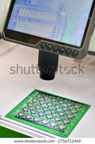 Digital microscope with LCD screen inspecting electronic circuit board in high resolution.