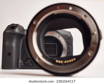 Digital mirrorless camera and compatible optical mount adapter on white background.
