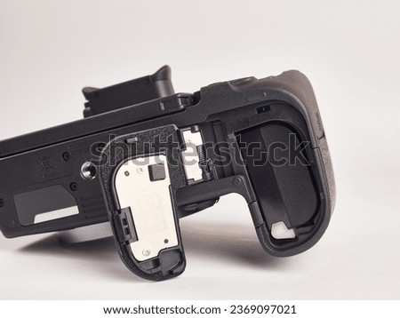 The digital mirrorless camera is shown below with the battery compartment open. Power supply of modern photo equipment.