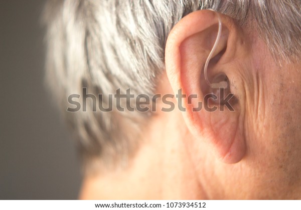 Digital\
modern hearing aid in the ear of aged old\
man.
