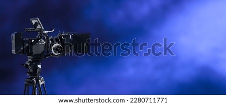 Digital movie camera filming in the dark with smoke and blue lightning background. television, broadcast, video, films studio or movie production background with copy space