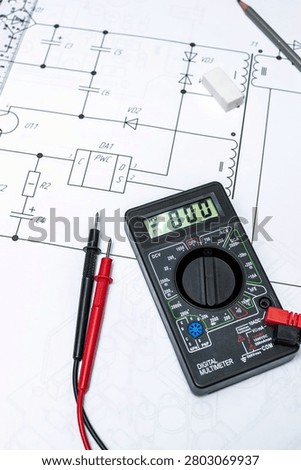 Digital multimeter testing probes on electronic schematic diagram