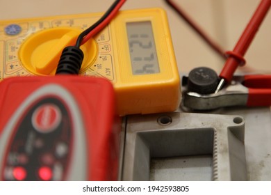 Digital multimeter volt meter screen with 12.74 volts digit on maintenance free car battery positive pin with red terminal cleat and automatic charger device backgroung, full charged car battery - Shutterstock ID 1942593805