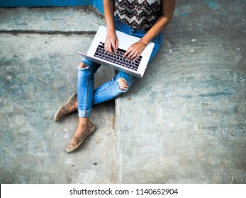 Digital Nomad Woman In Hipster Jeans Tap On Her Laptop While Sitting On Grey Stairs Outside In The Streets Of Morocco