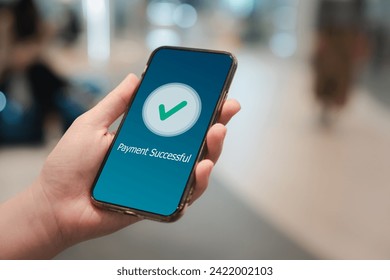 Digital online payment, online banking, online shopping and financial transaction success concept. Hand holding mobile phone and application showing payment successful message with green check mark. - Powered by Shutterstock