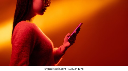 Digital people  Mobile banner  Online business  Social media marketing  Pink neon color light profile Asian girl using phone isolated orange gradient copy space background 