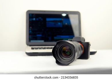 Digital photography workstation. Modern DSLR (mirrorless) digital camera,laptop and screen.