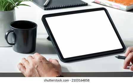 Digital portable tablet computer white screen mockup. Man working on digital tablet at his desk.
