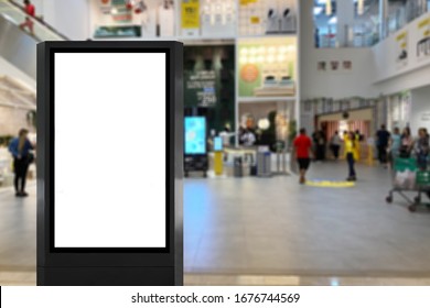 Digital Poster Kiosk Advertisement Board. Portrait Mode Screen Display At A Shopping Mall With People At The Background. Digital Signage With Blurred Shoppers. Light Box Inside A Mall