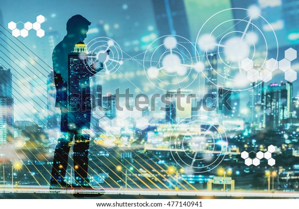 Digital\
revolution and Internet of Things concept. Double exposure of night\
city light and silhouette of business man standing and using smart\
phone with futuristic connection\
icons.