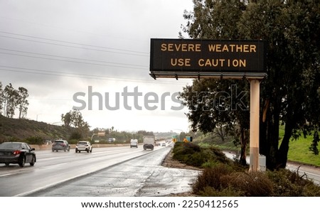 Digital sign at freeway stating Severe Weather Use Caution with wet freeway and traffic. The image is from the 15 freeway in San Diego County California