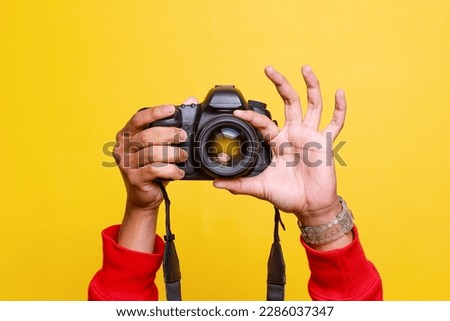 Digital single-lens reflex camera in hands. Man photographer makes photos. Male hands hold the camera close-up and adjust lens. 