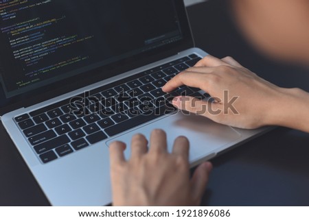 Digital software or application development, business technology concept. Programmer, man software developer coding HTML, programming Javascript on laptop computer screen, over shoulder view close up