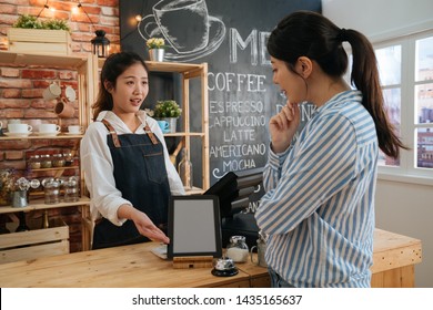 digital tablet with blank screen in coffee shop. coffeehouse female worker hands showing gesture with menu on mobile pad in bar counter and talking to customer. lady client thinking while take order.