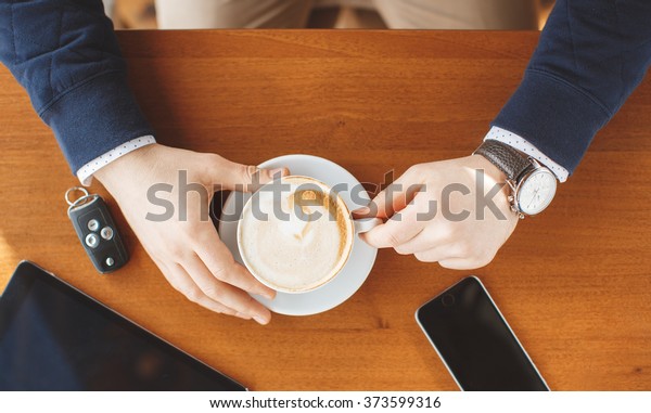 Digital\
tablet with blank screen in coffee shop cafe. Man\'s hands with\
coffee cup. car keys, smartphone and digital tablet computer.\
business, education, people and technology.\
