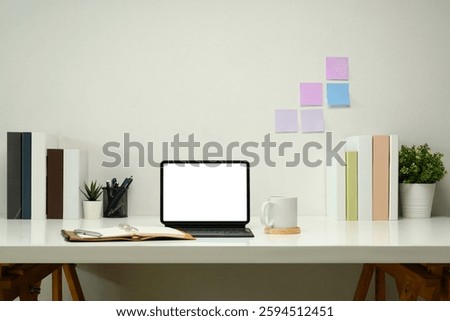 Digital tablet with a blank screen, leather planner and a cup of coffee on white table