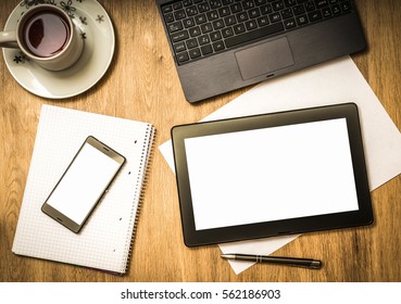 Digital tablet with blank screen and mobile phone on wooden table in business office