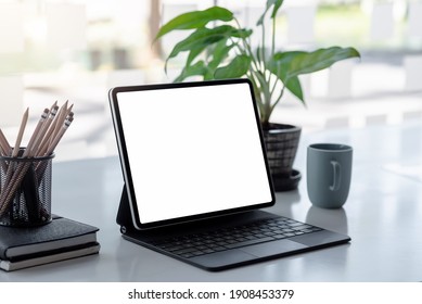 Digital tablet blank screen on the desk with coffee and book pencils at the office. - Shutterstock ID 1908453379