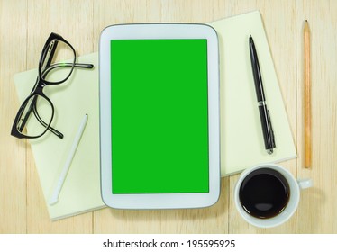 Digital tablet computer with blank green screen and cup of coffee on wooden desk. - Powered by Shutterstock