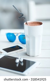 Digital tablet computer with cup of coffee on old wooden table in white cafe. Simple workspace or coffee break with web surfing. bue sunglasses