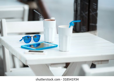 Digital tablet computer with cup of coffee on old wooden table in white cafe. Simple workspace or coffee break with web surfing. bue sunglasses