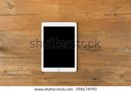 Digital tablet computer with isolated screen with clipping path on wooden background.