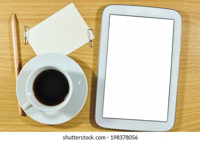 Digital tablet computer with note paper and cup of coffee on  wooden desk.