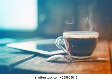 Digital tablet  and cup of coffee on old wooden desk. Simple workspace or coffee break in morning/ selective focus  - Powered by Shutterstock