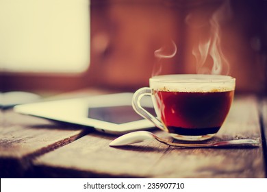 Digital tablet  and cup of coffee on old wooden desk. Simple workspace or coffee break in morning/ selective focus - Powered by Shutterstock