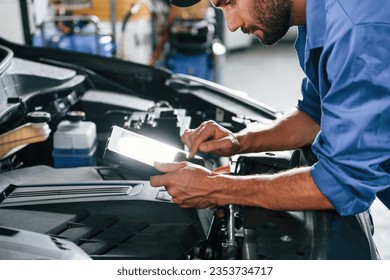 Digital tablet in hands. Auto mechanic working in garage. Repair service. - Powered by Shutterstock