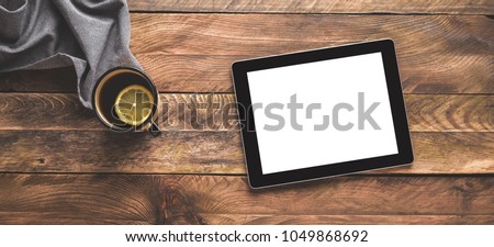 Digital tablet Ipad and a tea cup on wooden table. Flat lay. 