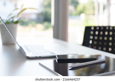 Digital tablet, mobile smart phone and laptop computer on white office table in meeting room with no people, computer devices and blurred background. Business and paperless office concept. - Shutterstock ID 2166464237