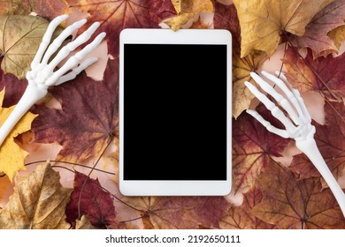 Digital tablet mock-up with monster skeleton hands and autumn leaves background. Happy Halloween, online shopping, studying, sales mockup. Fall flat lay, top view. Internet application template - Powered by Shutterstock