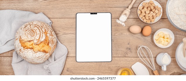 Digital tablet on kitchen table worktop on background with bread and utensils. Food recipes, online delivery, homemade food, cooking process. - Powered by Shutterstock